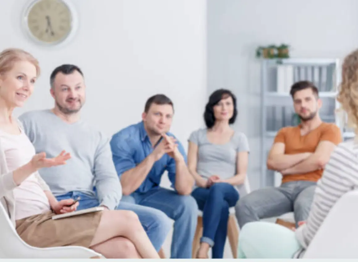A group of people sitting in a circle, engaged in a discussion or therapy session.